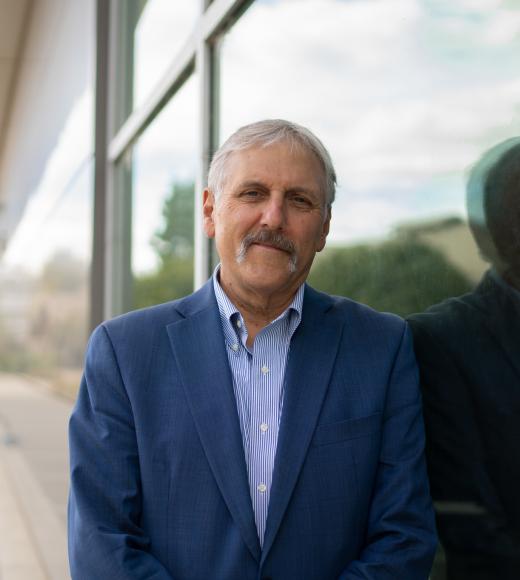 Dean of Engineering Richard L. Corsi wearing a blue blazer leaning against reflective glass facade