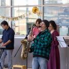 Colleagues performing together in a band; saxophonist in green plaid